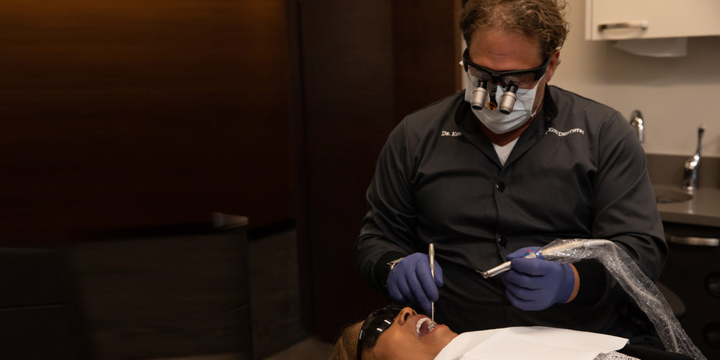 Prosthodontist Dr. Dean Kois performing laser periodontal treatment on african-american woman.