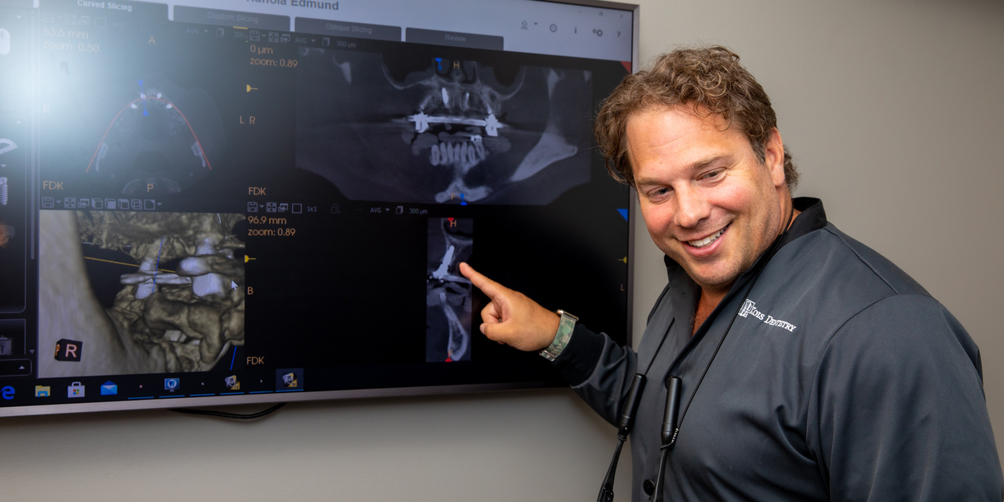 Prosthodontist Dr. Dean Kois pointing at 3D images of a patients jaw on a monitor.