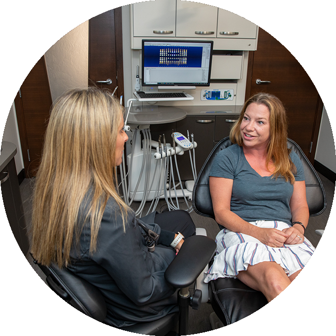 Female patient in dental chair discussing her dental crown treatment with cosmetic dentist, Dr. Tara Kois