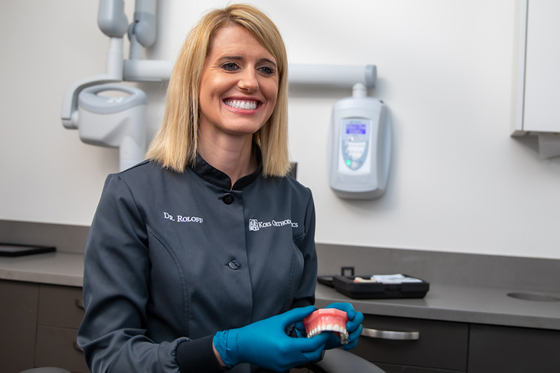 Orthodontist Dr. Brienne Roloff smiling holding a model of a lower arch of teeth.