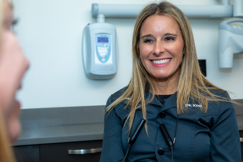 Cosmetic dentist Dr. Tara Kois smiling at female dental crown patient.