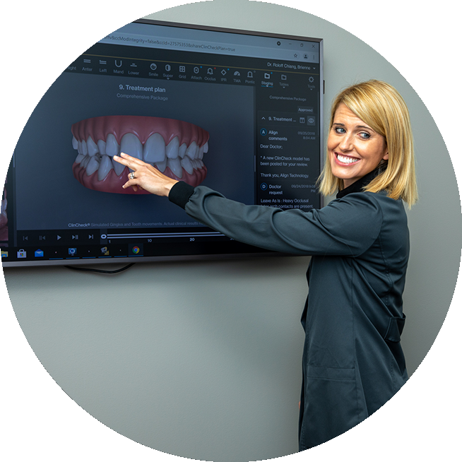 Orthodontist Dr. Brienne Roloff pointing at a monitor going over orthodontic treatment plan.