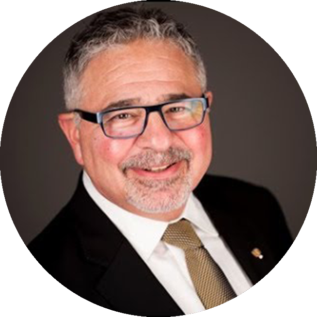 Smiling prosthodontist Dr. John Kois wearing glasses, and a black suit and gold tie.