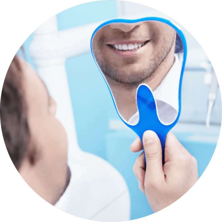 Man looking in mirror admiring his smile after gum recession treatment.