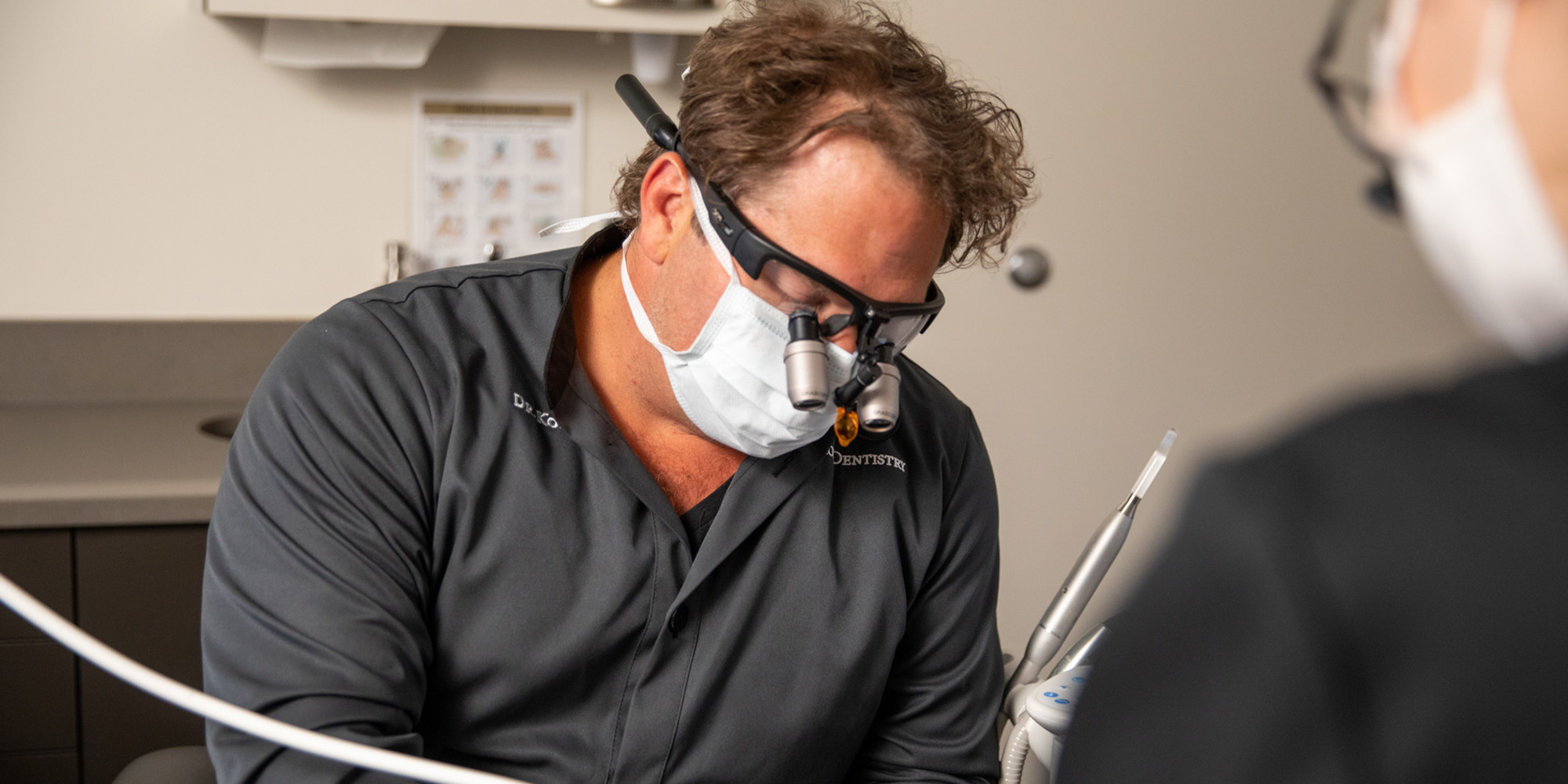 Prosthodontist Dr. Dean Kois in scrubs performing a dental implant procedure.