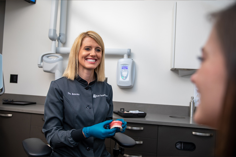 Orthodontist Dr. Brienne Roloff holding dental arch model discussing treatment plan with female patient.