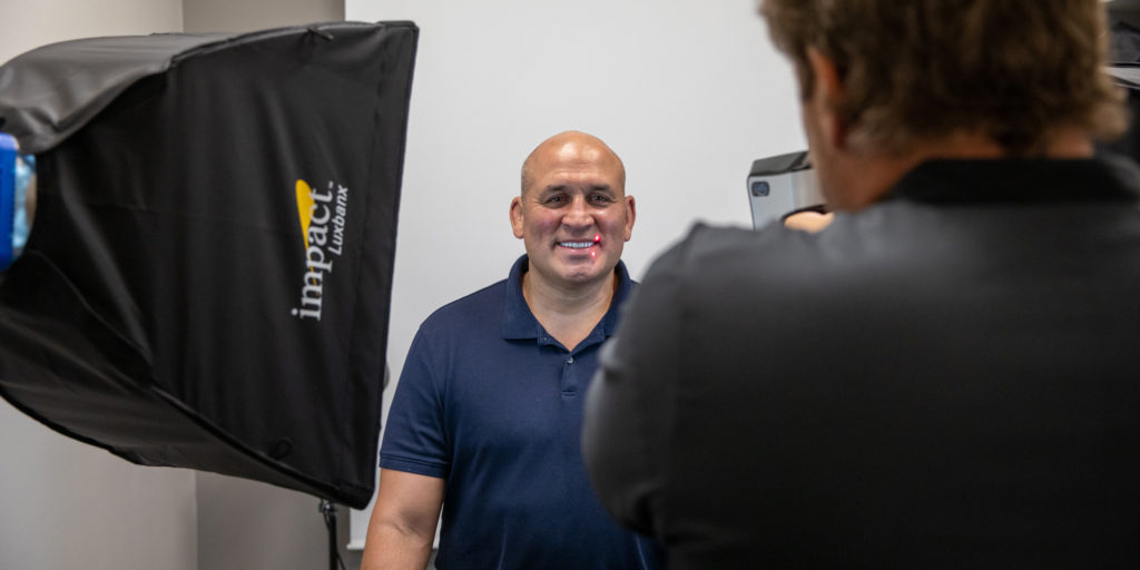Ex-UFC fighter Ivan Salaverry smiling showing his full arch dental implants while Dr. Dean Kois takes a picture.while